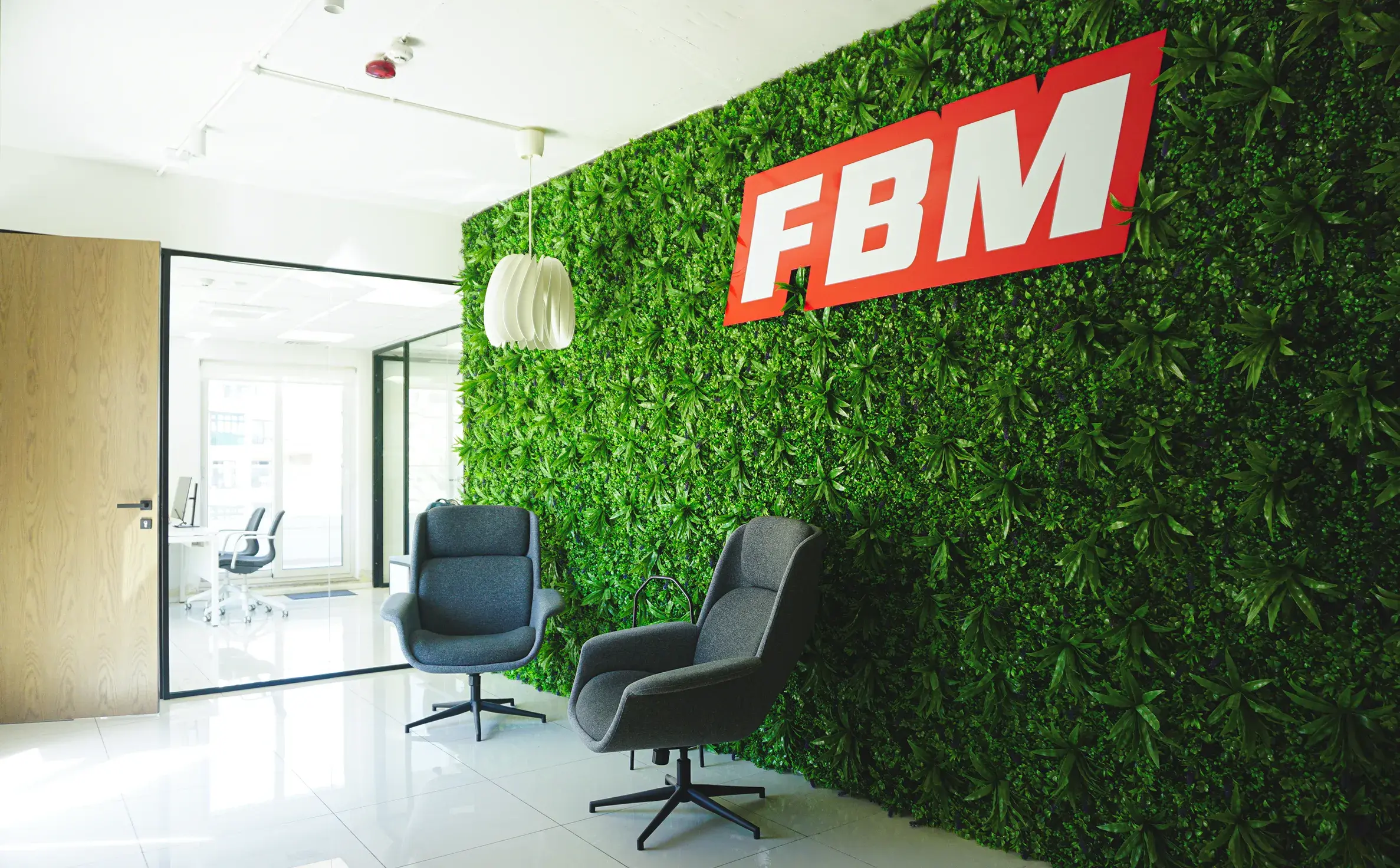 A social space in the FBM office with a green wall and the casino gaming brand above two chairs