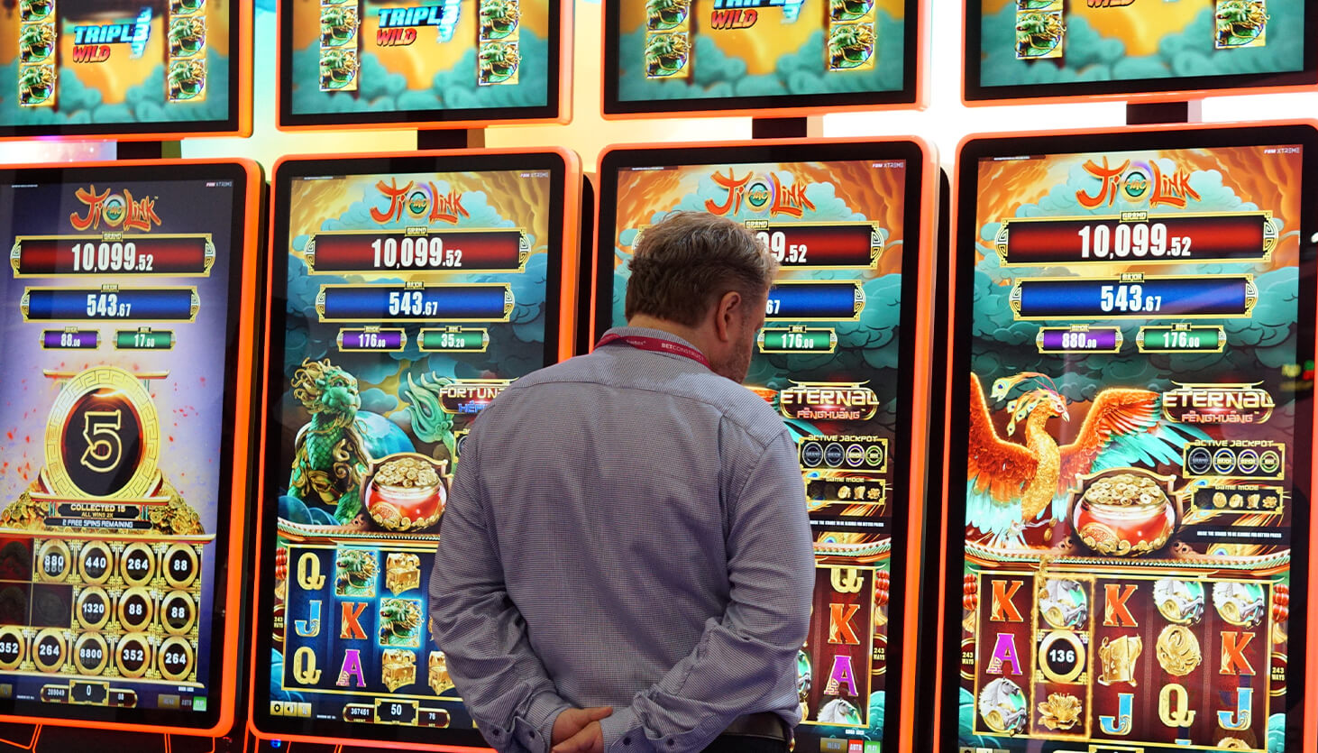 An FBM representative checks the last details about the Ji Hao Link slots product at a casino tradeshow.