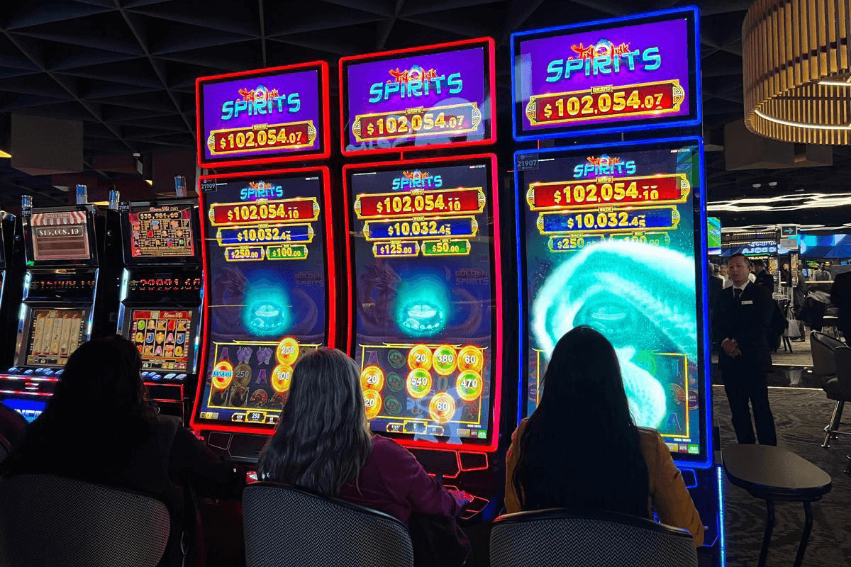 Esta imagen muestra a tres jugadores mexicanos disfrutando de los slots Jin Qián Link Spirits desarrollados por FBM en una sala de casino en México.