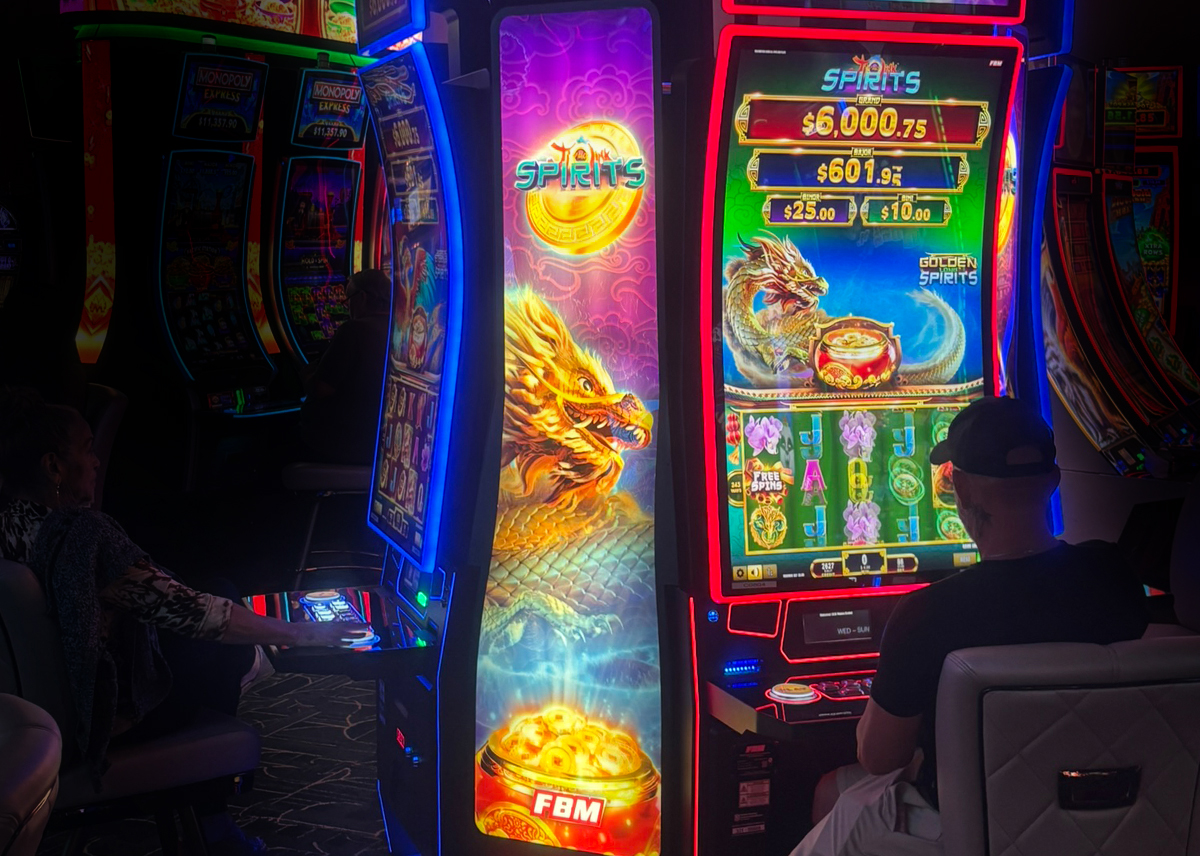 The image shows a player enjoying FBM's Jí Hǎo Link™ Spirits games at Gulfstream Park Casino