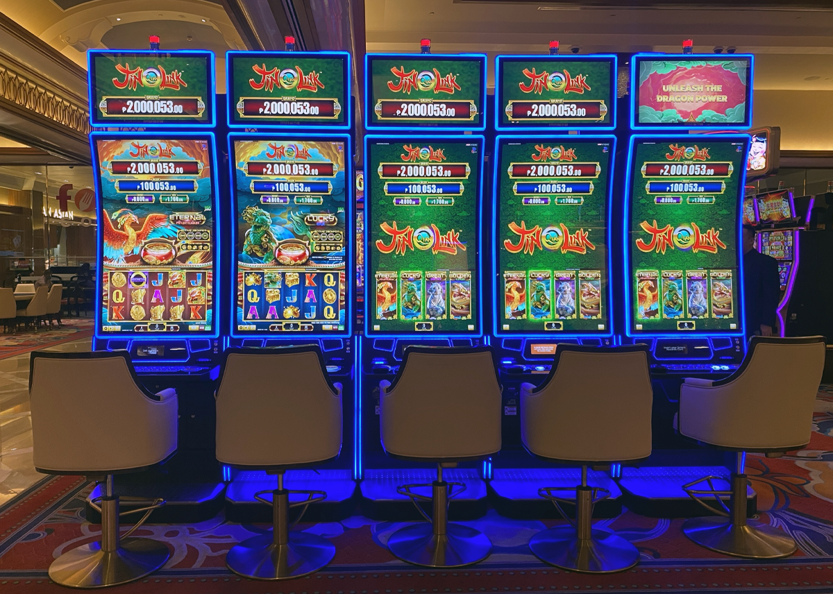 Esta imagen muestra cinco gabinetes de casino Auria de FBM ejecutando los juegos de video rodillos Jin Qián Link.