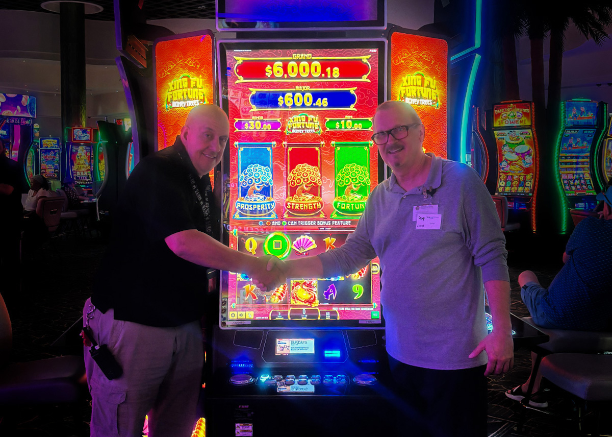 The image shows the Gulfstream Casino and FBM representatives shaking hands in front of FBM's last install Xing Fú Fortune Money Trees.