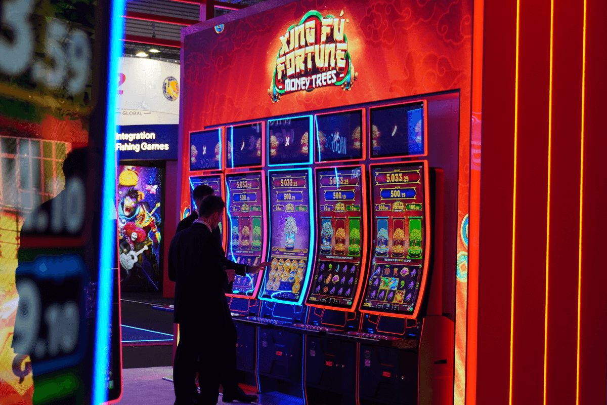 This image shows an FBM employee explaining a client everything about the Xing Fú Fortune Money Trees slot in a tradeshow.