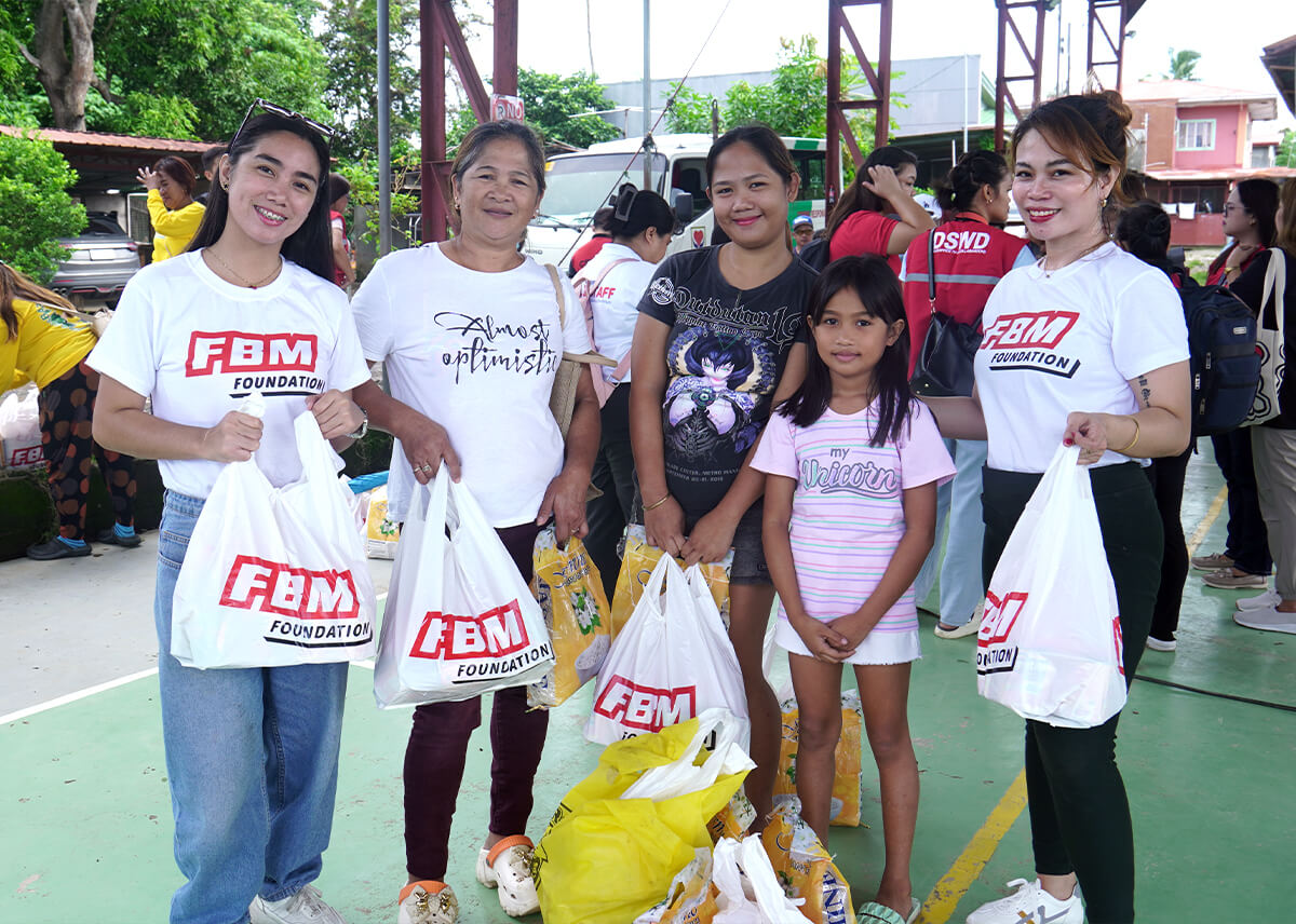 FBM Foundation volunteers and beneficiaries pose together with their relief packs, showing the power of community and solidarity.