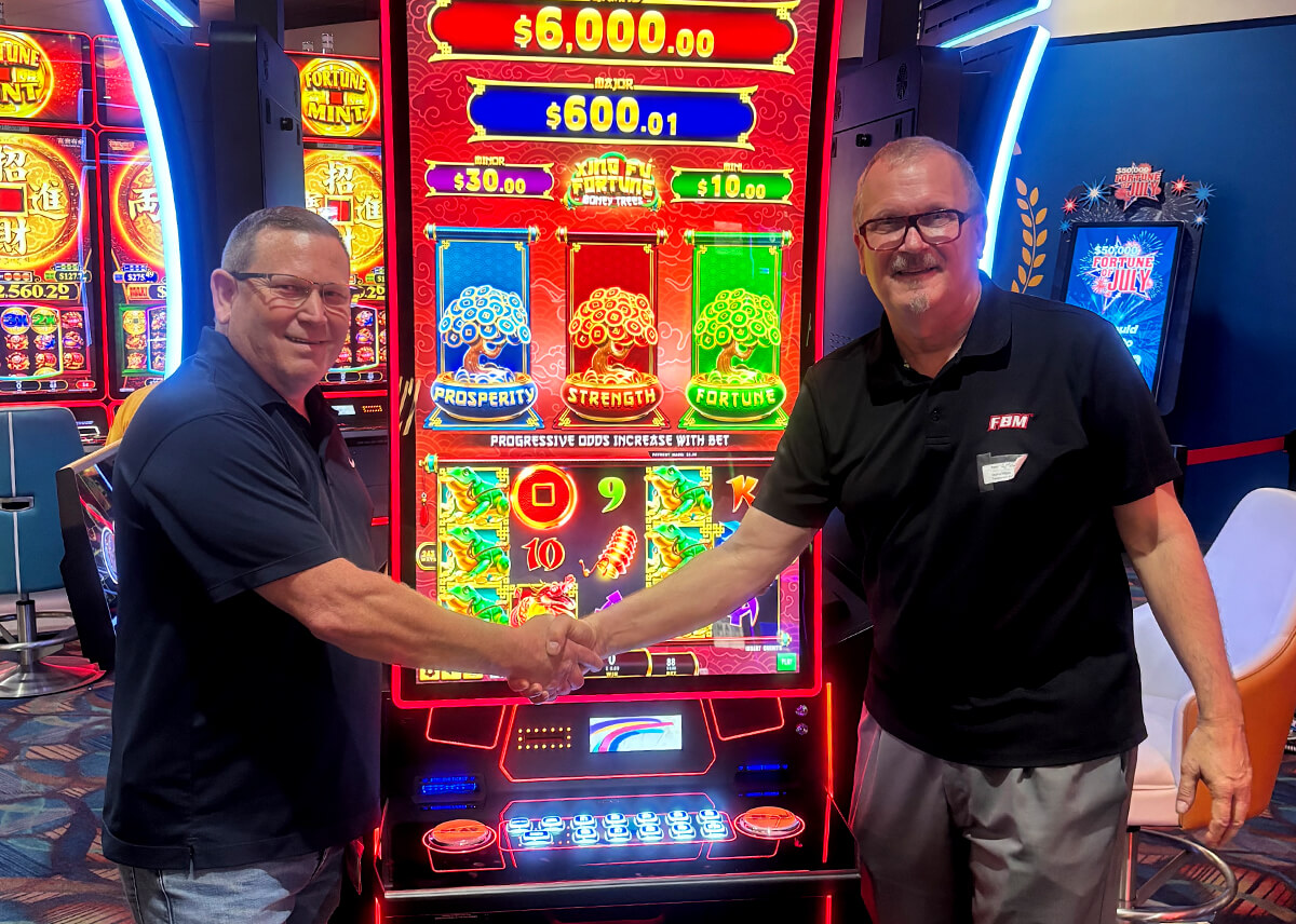 The image shows the FBM representative Mike Medlin with Neal Elliot, director of slot operations at Casino Miami, after concluding the installation of Xing Fú Fortune Money Trees at Casino Miami