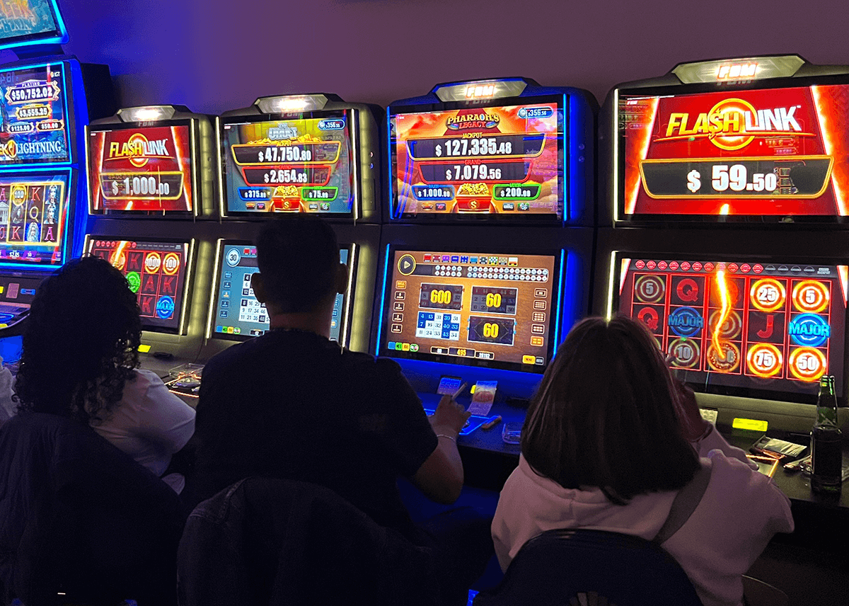 This image shows three players enjoying FBM's Flash Link bingo games in a Mexican casino room.