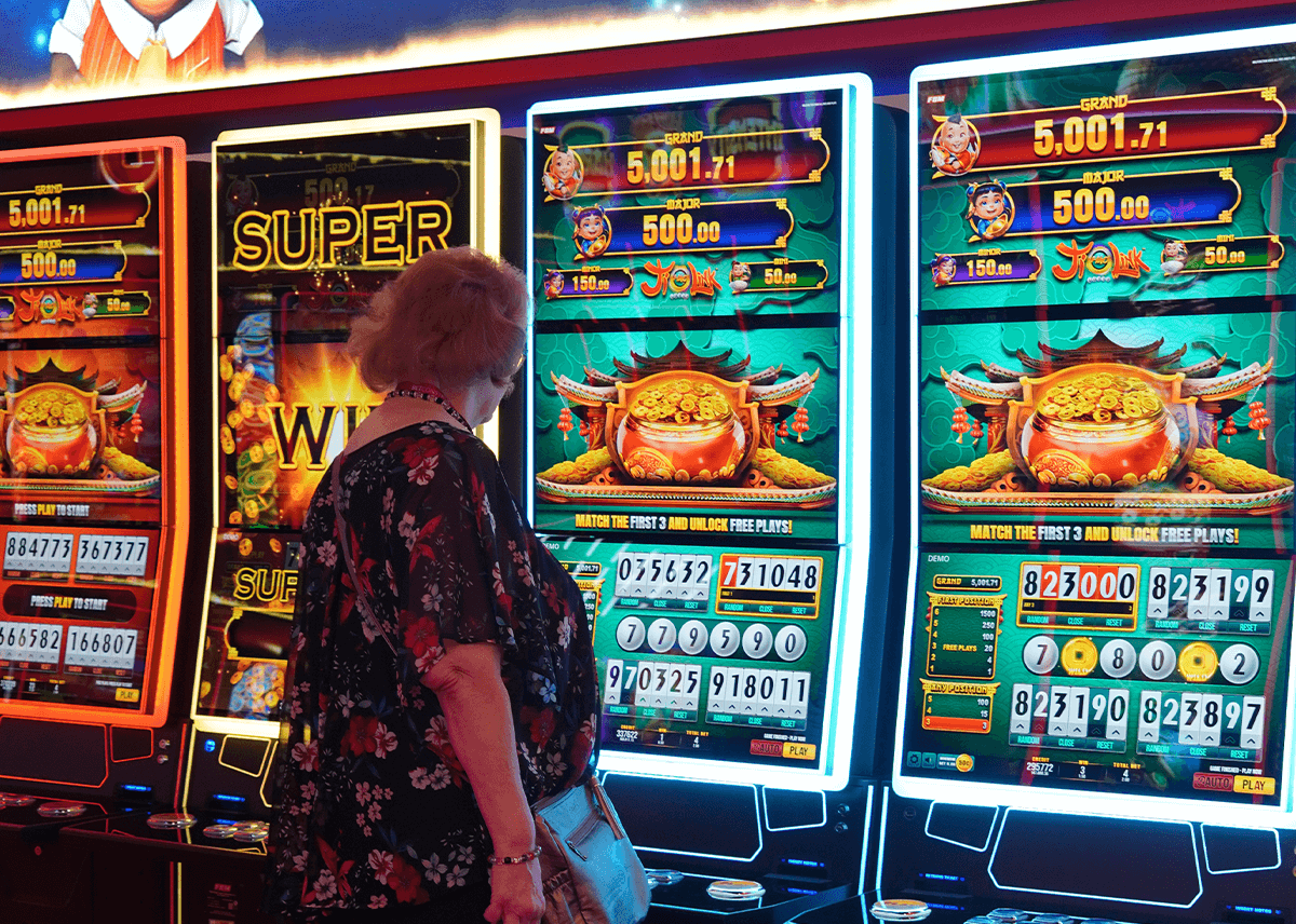 A few FBM Auria Casino Cabinets showcasing the Bull’s Champion Lotto game during G2E Las Vegas with a visitor trying the game.